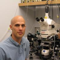 A photo of Jeremy Seamans with a microscope